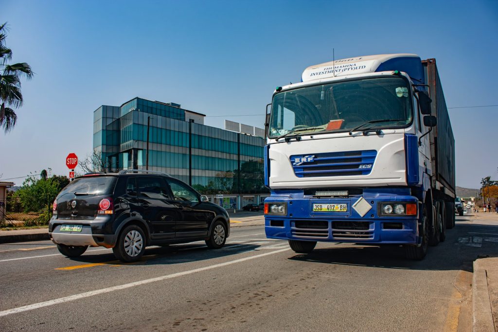 Ein LKW und ein Auto teilen sich eine sonnige Straße.